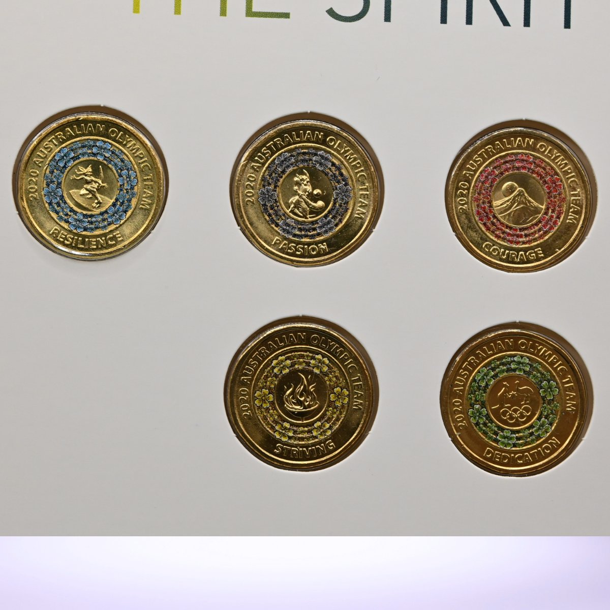 Five 2020 $2 Tokyo Olympics coins with cherry blossoms in blue, black, red, yellow and green - reverse of coins