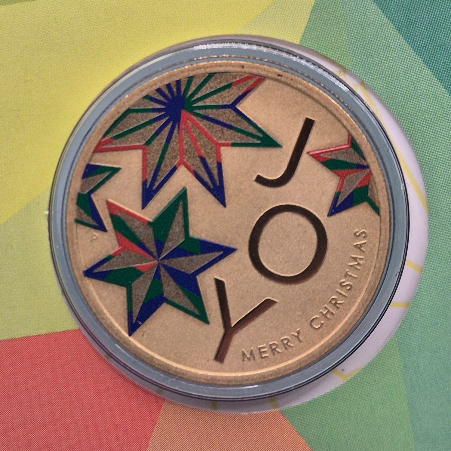 Coloured 2022 $1 coin with text 'Joy' 'Merry Christmas' and star designs - close up reverse 
