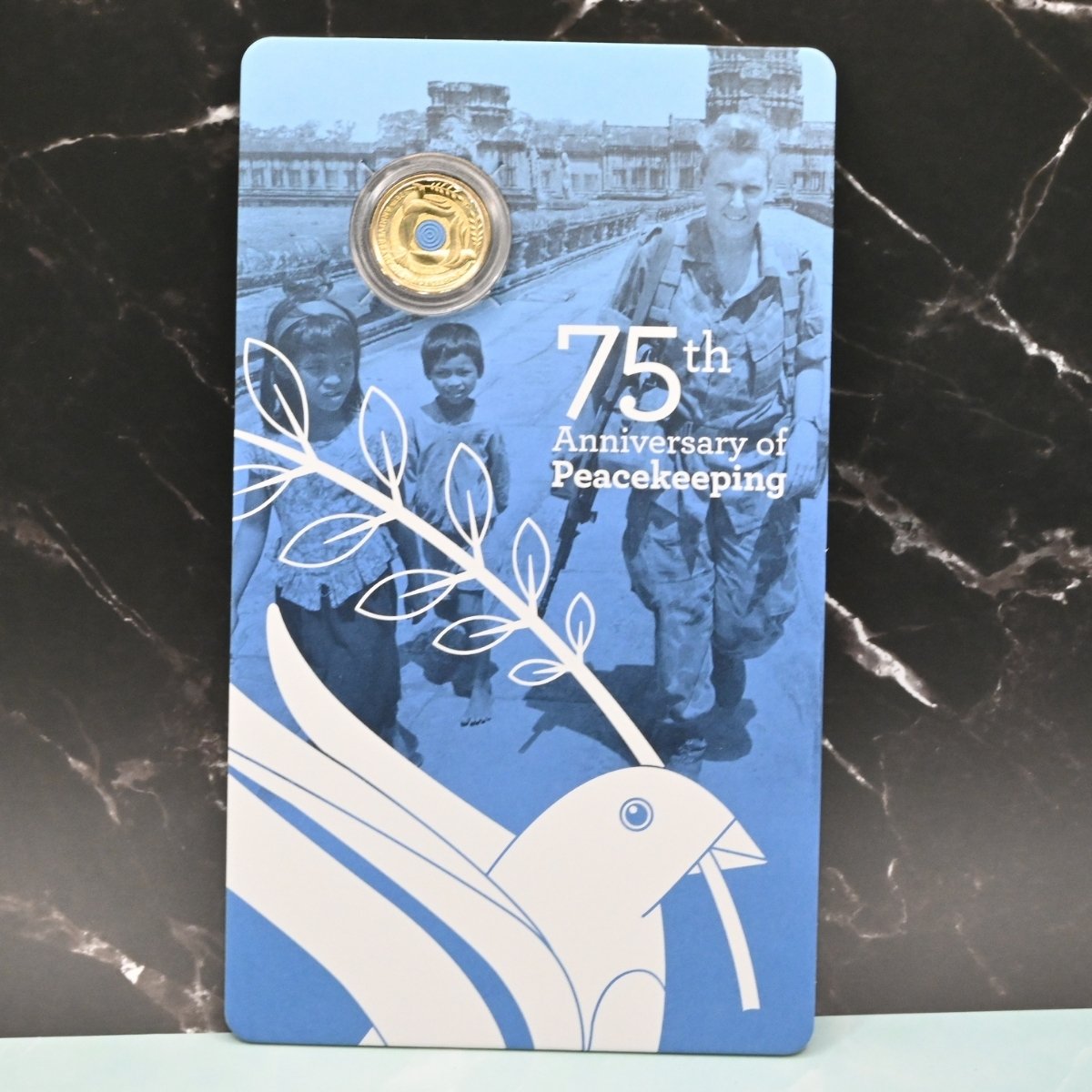 2022 $2 'C' Mintmark Peacekeeping coin on large card featuring a blue dove and text '75th Anniversary of Peacekeeping'