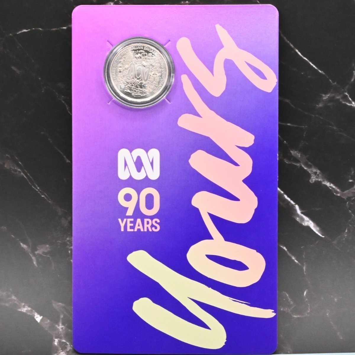 Purple card with '90 Years' text, the ABC logo and a 2022 20c coin