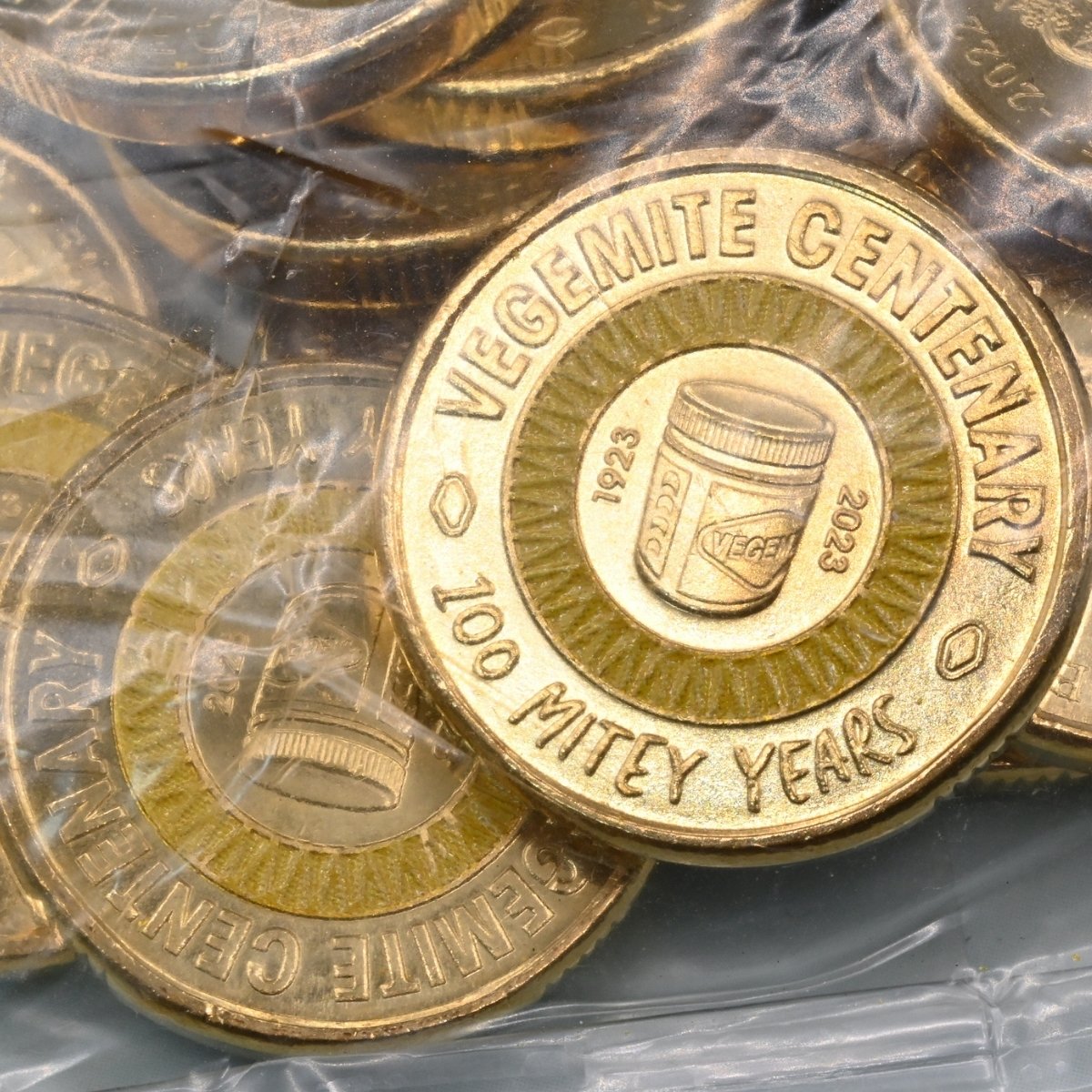 2023 $2 close up of reverse side of coins with 'Vegemite Centenary' text and yellow colour design, in security bag.