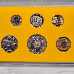 Set of six 2023 Royal Australian Mint Vegemite Year set coins including coloured $1 Vegemite on Toast in a display case with a yellow background - reverse side