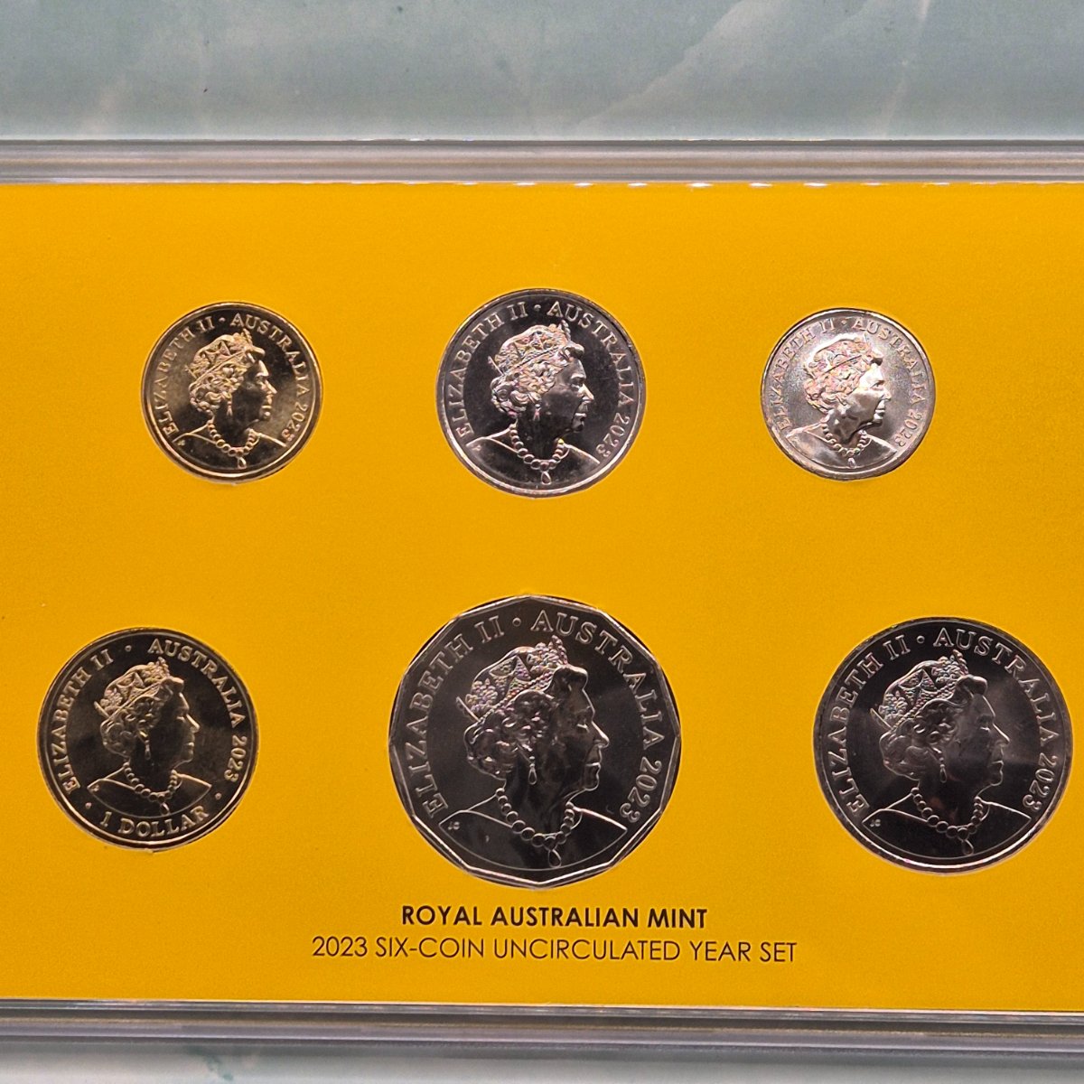 Set of six 2023 Vegemite Year Mint Set coins from the Royal Australian Mint on a yellow background - obverse side