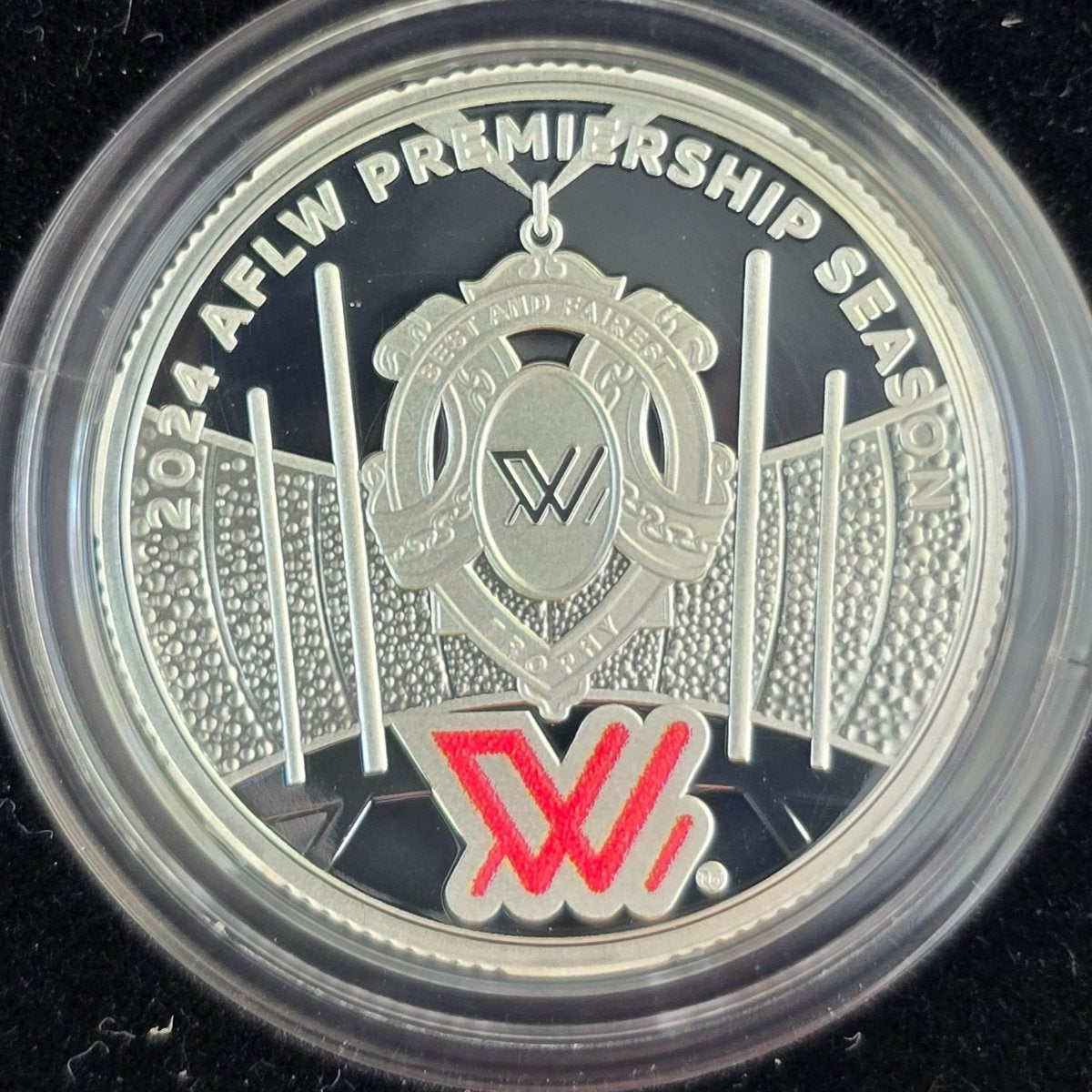 Silver $1 coin with AFLW Premiership Season 2024 logo and text on a black background