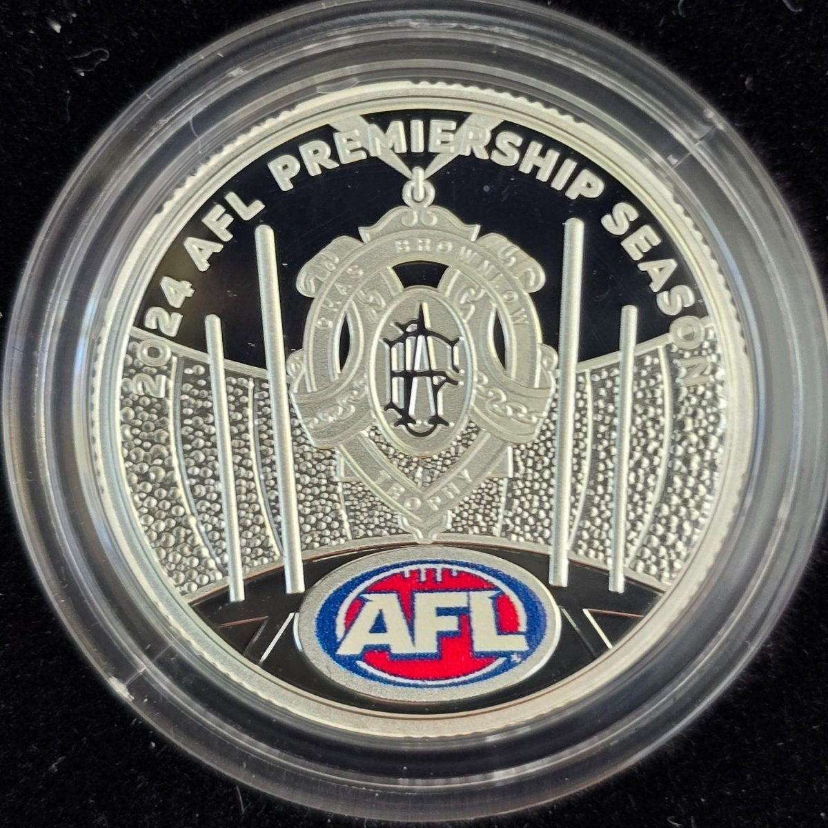 2024 $1 silver coin with AFL Premiership Season text and coloured logo on a black background
