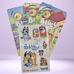 Collection of 'Bluey' themed items including carded coins and a sticker sheet on a light purple background