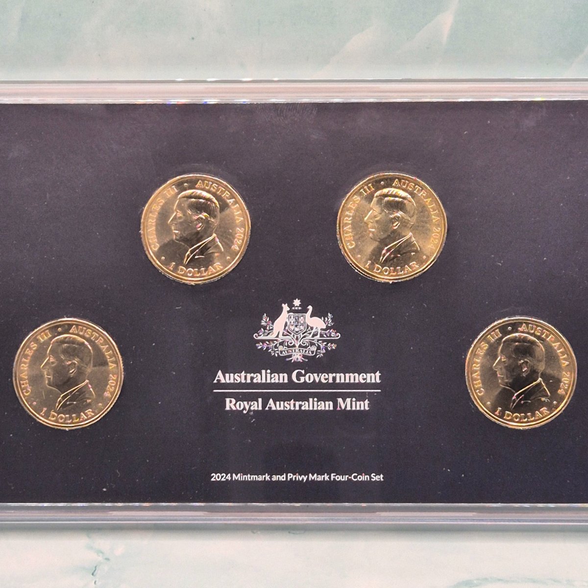 Four obverses of 2024 $1 Out of this World coins in plastic packaging with text Australian Government Royal Australian Mint