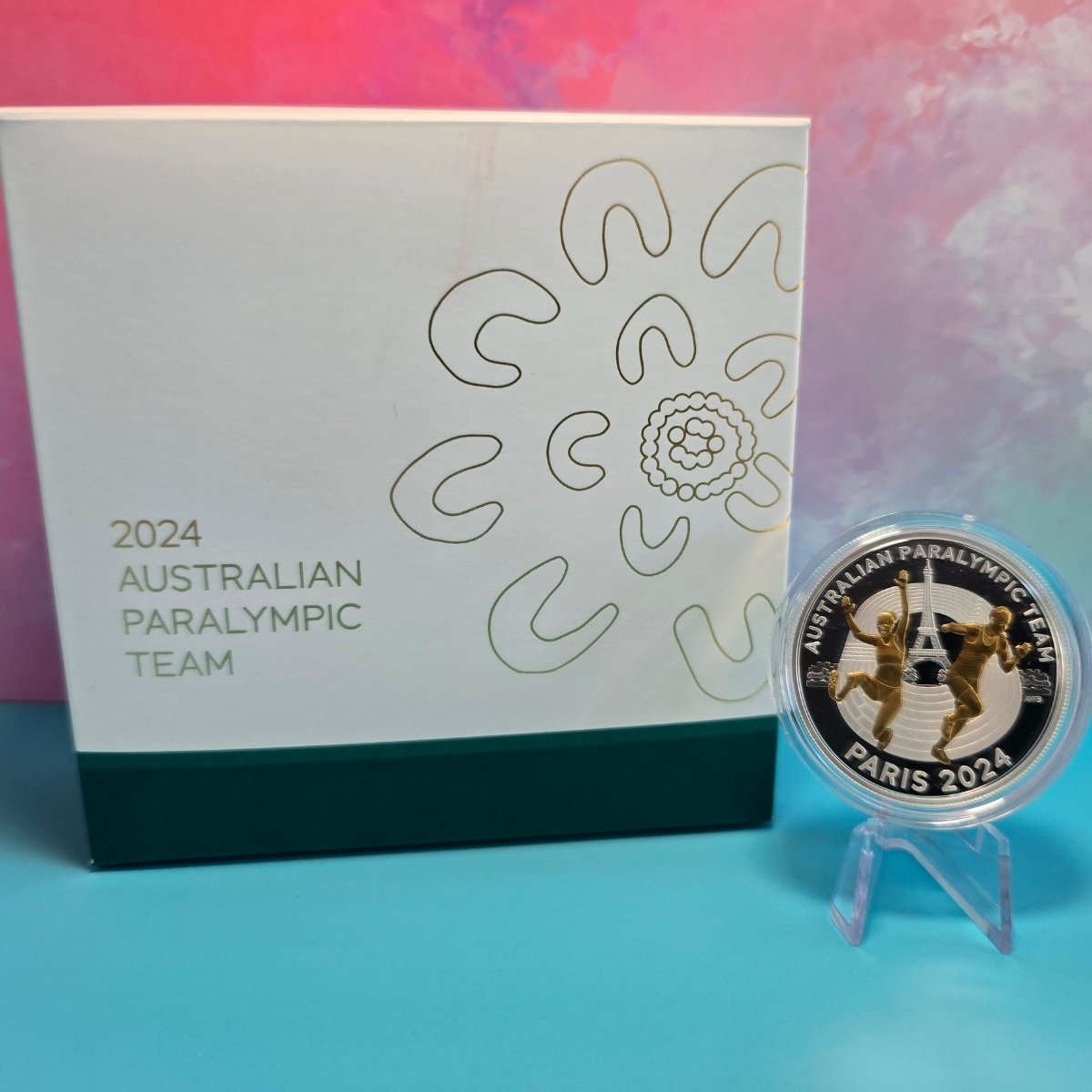 2024 $5 Selectively gold plated silver coin with Australian Paralympic Team design in front of a branded box on a colorful background